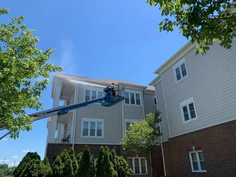 A Supreme Clean service worker in a lift spraying a roof