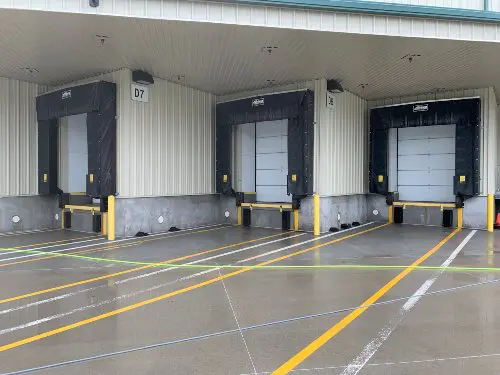 Three loading docks in the back of a commercial building with a recently cleaned and sealed concrete parking locations