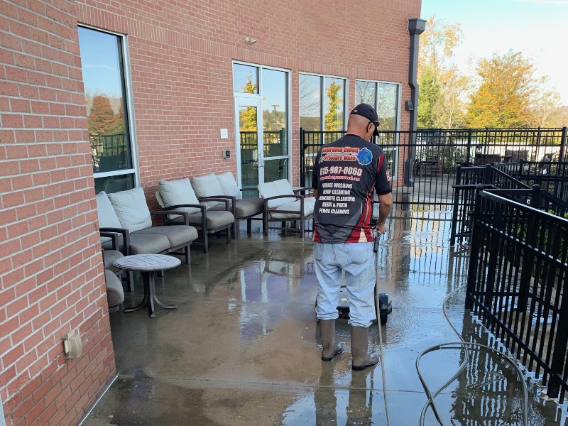 A Supreme Clean staff member washing the concrete lounge area of a commercial property