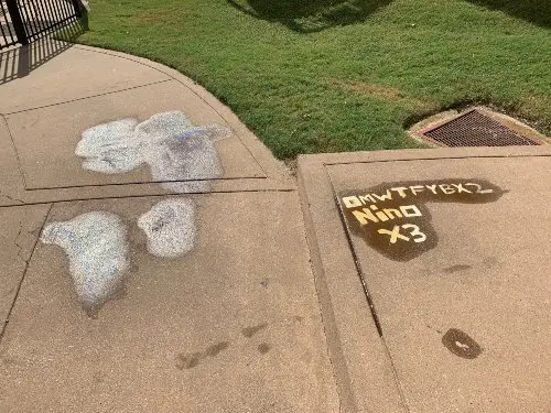 A stained and graffitied concrete walkway in need of professional cleaning