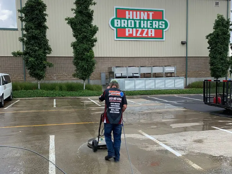 A service professional cleaning the parking lot of Hunt Brothers Pizza