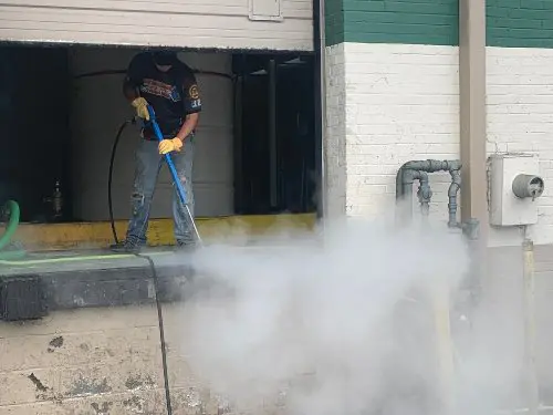 A Supreme Clean employee pressure washing a loading dock