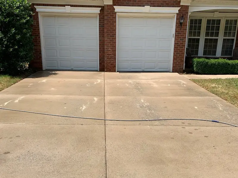 A run down concrete driveway with dirty streaks and stains on it
