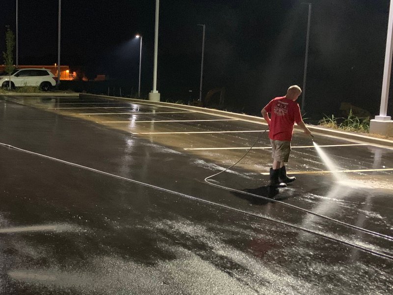 A Supreme Clean staff member washing an empty parking lot at night