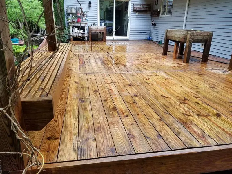 A closeup of a cleaned wooden deck with a bench to sit on