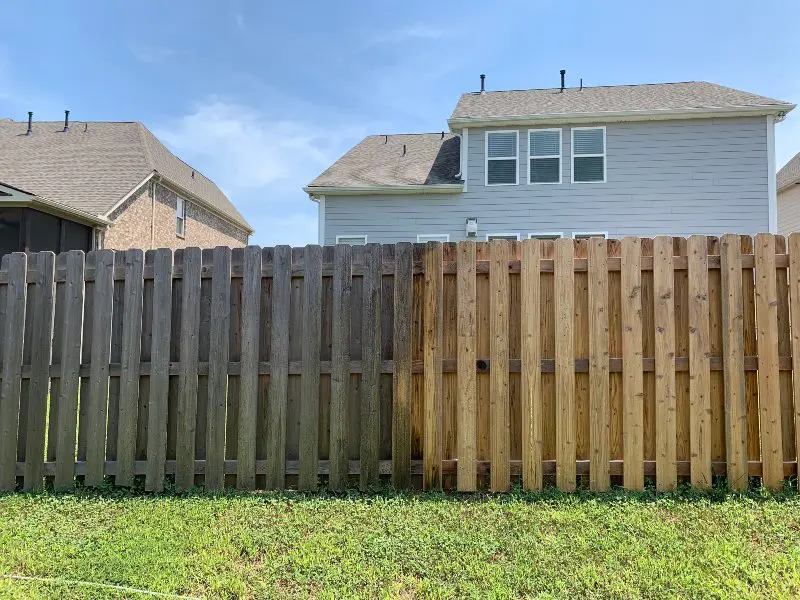 A disgusting wooden fence in the middle of being professionally cleaned