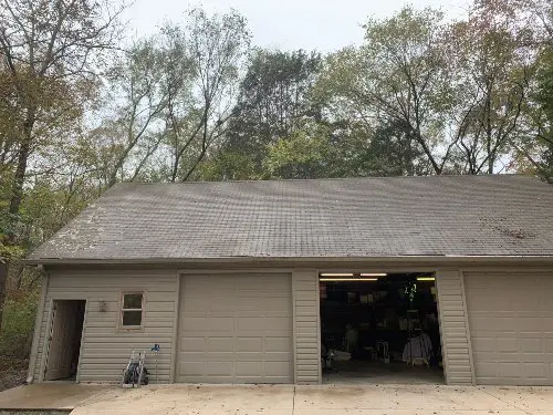 A three door garage with a dirty roof in need of soft washing