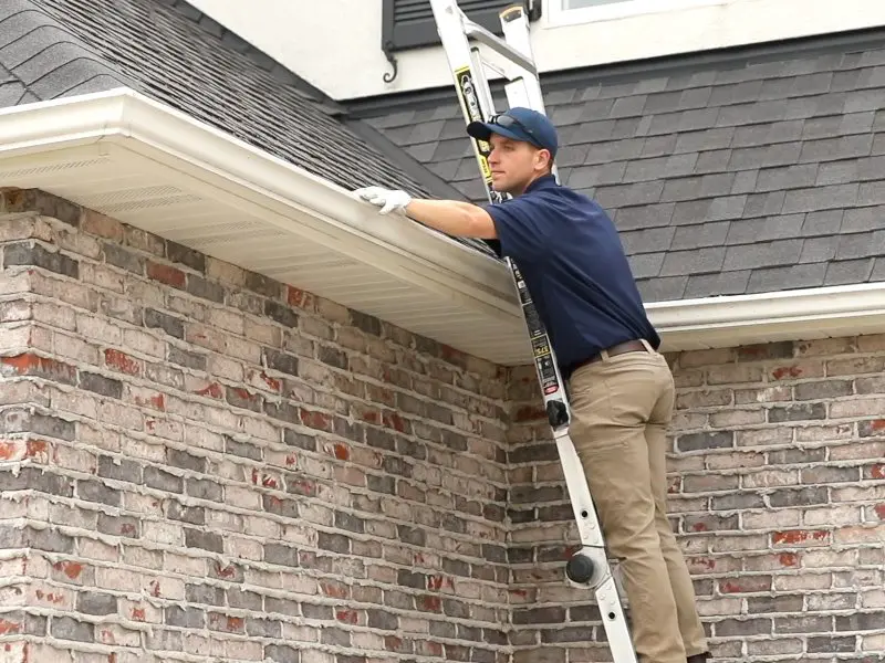 Technician hand cleaning gutters on a nashville home.